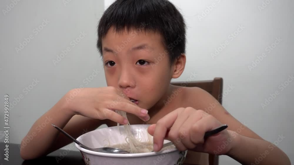 Chinese kid eat white rice noodle with fork and spoon Chinese kid eat white rice noodle with fork and spoon