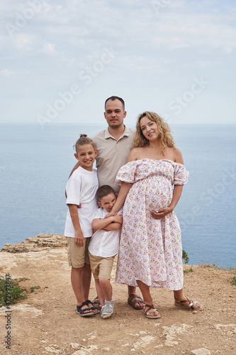 beautiful family on the background of the seascape. mom is pregnant, two cheerful sons and dad