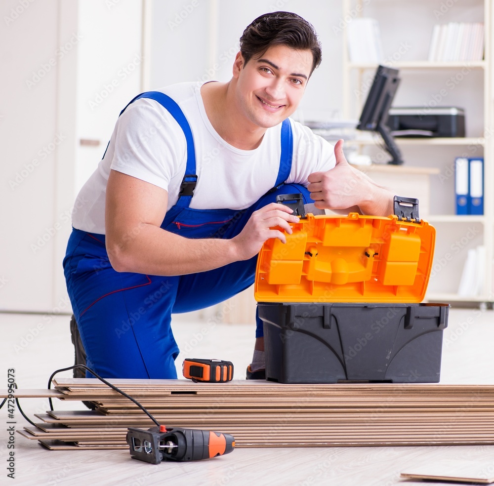Young worker working on floor laminate tiles Young worker working on floor laminate tiles