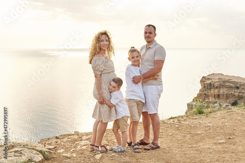 family on the seaside, the youngest son hugs his pregnant mother. eldest son hugs dad