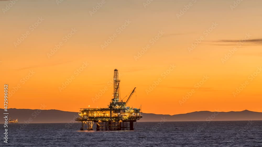 An oil platform off the coast of California lights up as the sun sets. Notice the interesting natural heat haze as it periodically distorts the platform until evening arrives and the weather cools. An oil platform off the coast of California lights up as the sun sets. Notice the interesting natural heat haze as it periodically distorts the platform until evening arrives and the weather cools.
