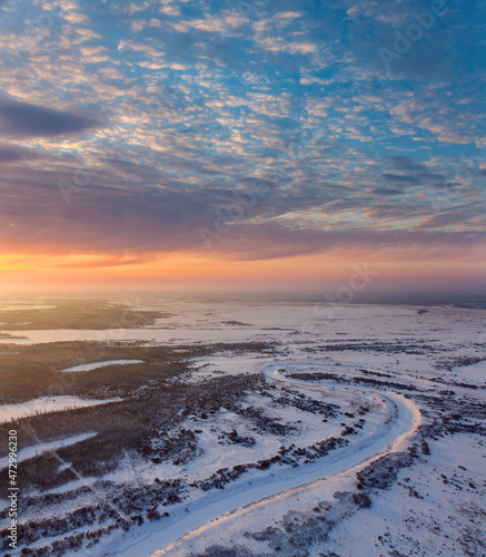 Forest river with beautiful sunset in winter, air photo