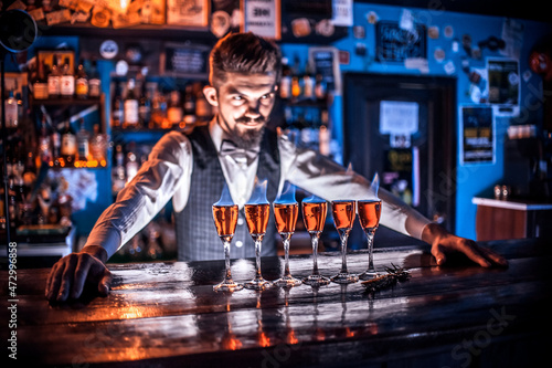 Charming barman places the finishing touches on a drink at the bar counter