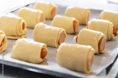 Homemade mini sausage wrapped in puff pastry in oven tray prepare for bake.