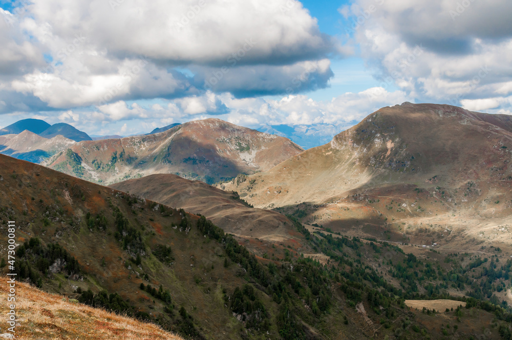 Bergige Landschaft in Österreich.  Blick von einem hochgelegenen Punkt auf  eine Gebirgskette. Sonniger Herbsttag mit dramatischen Wolken