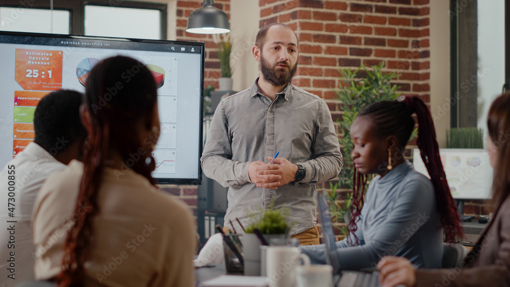 Close up of worker presenting business strategy on display with data analysis, working on company growth and development with colleagues. Man talking to workmates about project planning Close up of worker presenting business strategy on display with data analysis, working on company growth and development with colleagues. Man talking to workmates about project planning