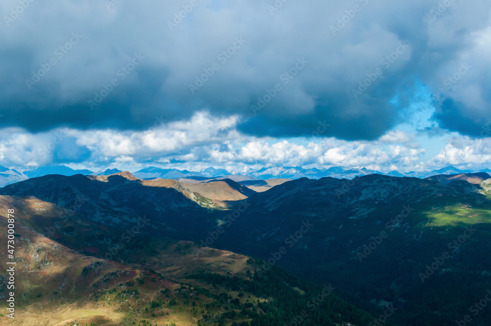 Bergige Landschaft in Österreich.  Blick von einem hochgelegenen Punkt auf  eine Gebirgskette. Sonniger Herbsttag mit dramatischen Wolken