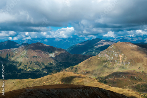Bergige Landschaft in Österreich. Blick von einem hochgelegenen Punkt auf eine Gebirgskette. Sonniger Herbsttag mit dramatischen Wolken