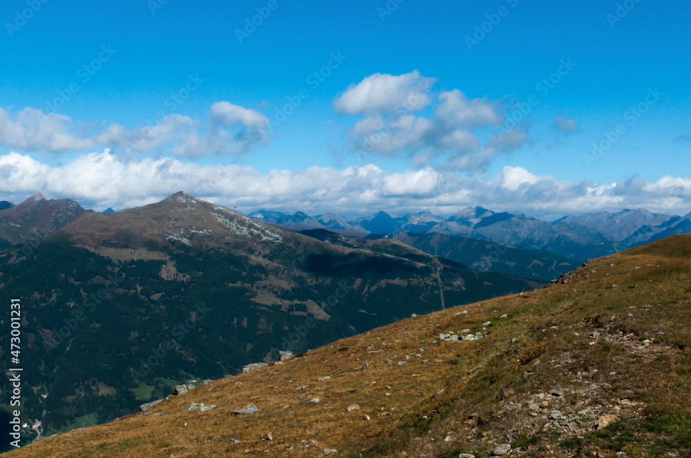 Fototapeta premium Bergige Landschaft in Österreich. Blick von einem hochgelegenen Punkt auf eine Gebirgskette. Sonniger Herbsttag
