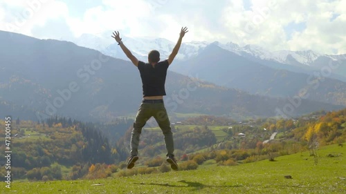 Wallpaper Mural young handsome slender man jumps and claps his hands against background of autumn mountains. Georgia Svaneti. He is delighted and pleased with beauty of mountainous terrain and nature. slow motion Torontodigital.ca