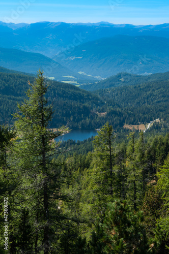 Bergige Landschaft in Österreich. Blick von einem hochgelegenen Punkt auf eine Gebirgskette und einem kleinen See im Tal. Sonniger Herbsttag