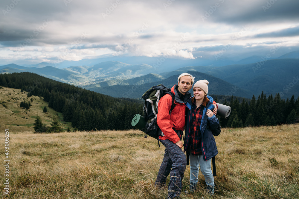 Couple traveler with backpacks in the alps, hikers in the mountains, happy active lifestyle, hiking man and woman traveling together