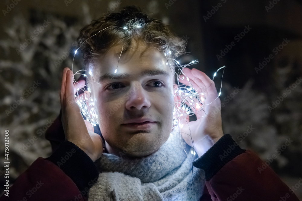 young handsome guy in headphones from a garland, new year and christmas concept
