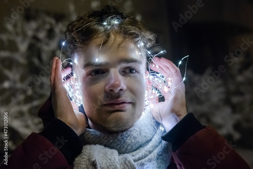 Obraz na płótnie young handsome guy in headphones from a garland, new year and christmas concept w salonie
