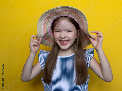 portrait of a cute smiling little girl in a hat on a yellow background