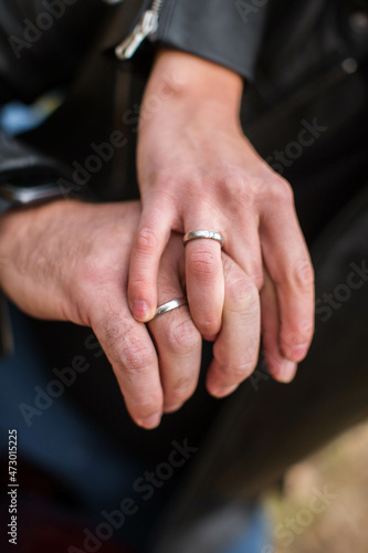 Close-up photo of man and woman hands with wedding rings in autumn park