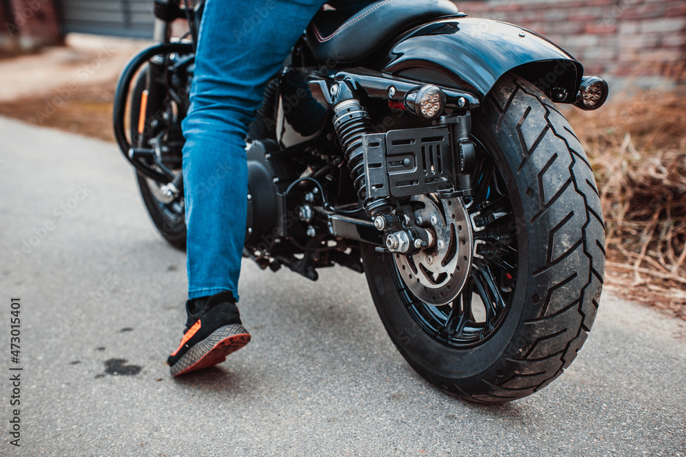 Naklejka premium Autumn season motorcycle on the road. The rubber protector of the rear wheel is new. Biker in jeans