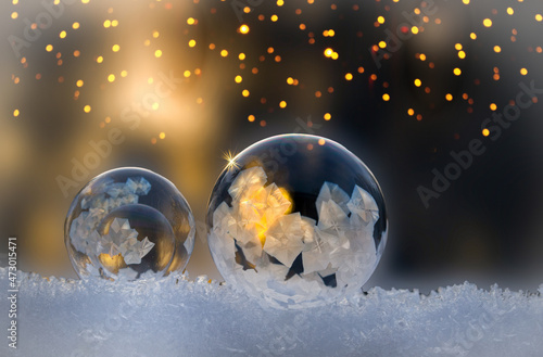 Christmas. Glowing frozen soap bubble with fireflies and golden background  copy space