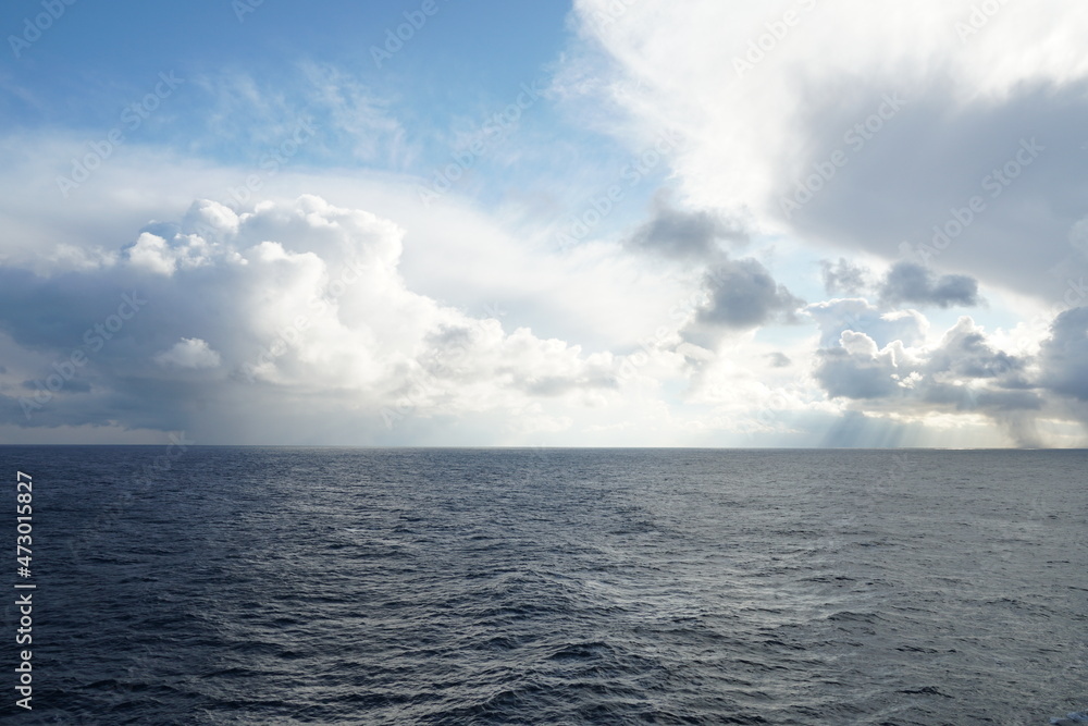 View from vessel on heavy rainfall clouds bringing abundant rainfall and atmospheric precipitation partly interrupted by bleu sky observed on Pacific ocean in winter season during calm weather.