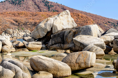 A group of granite boulders on the seashore at the foot of the mountain range.