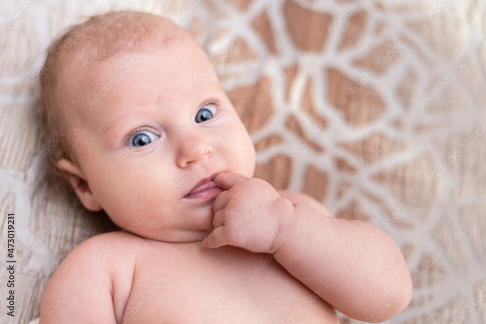 Portrait of a beautiful baby girl lies on a white sheet in her room Portrait of a beautiful baby girl lies on a white sheet in her room