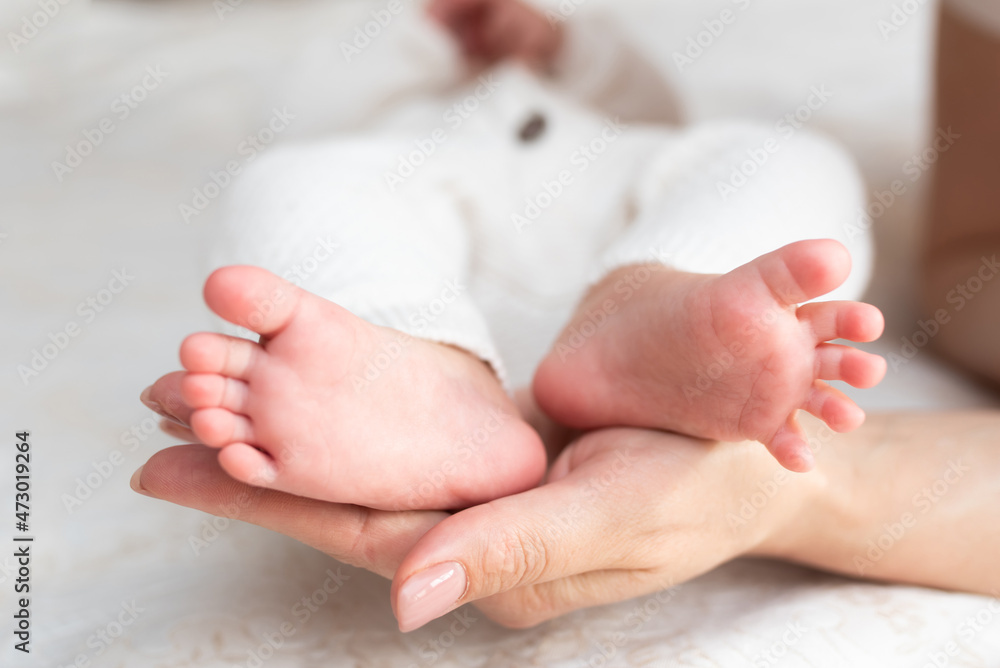 Mother hugs legs of newborn baby with hands Mother hugs legs of newborn baby with hands
