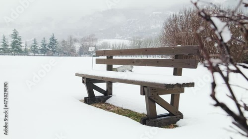 Winter in the park. A bench covered with snow among the trees