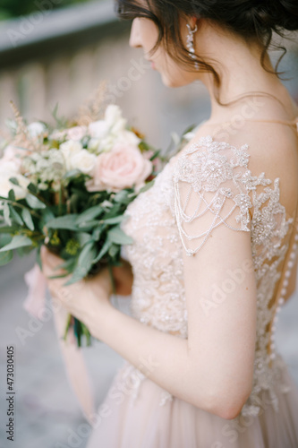 Bride in a lace dress with a bouquet of flowers. Side view. Close-up