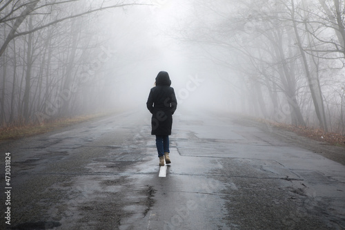 Valokuva Lonely woman walking in fog away road