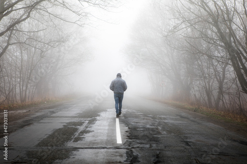 фотографія Lonly man  walk away into the misty foggy road in a dramatic mystic scene