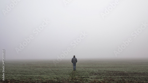 Lonly man walk away into the misty foggy road in a dramatic mystic scene. Guy walking in a foggy autumn landscape