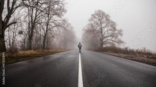 фотографія Lonly man  walk away into the misty foggy road in a dramatic mystic scene