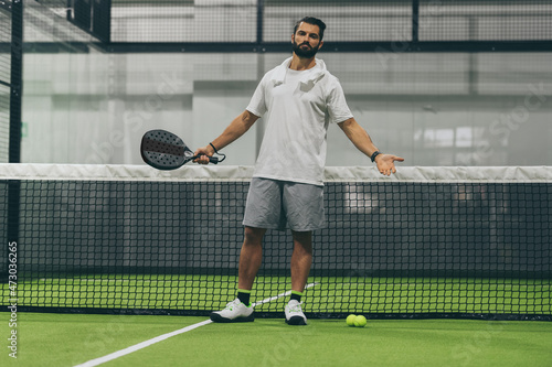 Beautiful man playing paddle tennis, racket in hand exults after a win. Young sporty boy at the end of the match. Sweaty padel athlete ready to take shower. Sport, health, youth and leisure concept photo