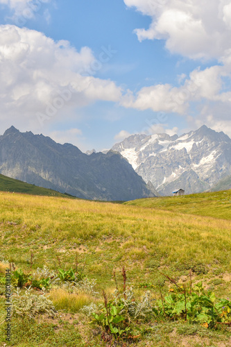 Summer mountain landscape in Svaneti region, Georgia, Asia. Snowcapped mountains in the background. Blue sky with clouds above. Georgian travel destination.