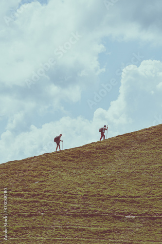 Man and woman climbing up a hill. Mountain hiking. Teamwork concept. Motivational background.