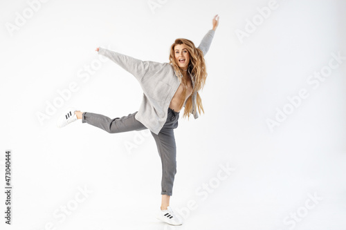 The woman emotionally jumps up, arms outstretched and leg raised. Isolated over white background.