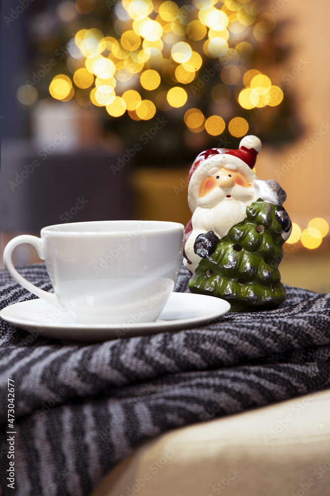 Φωτογραφία A cup of tea and a figure of Santa Claus on the background of a Christmas tree,