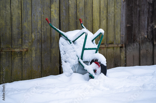Wheelbarrow at a wall in snow.