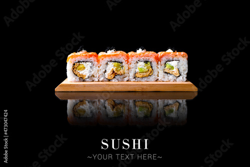 Salmon Japanese sushi inside out roll with avocado, cream cheese. Served on wooden board. Asian dish on black background with reflection. Banner with Text space 
 photo
