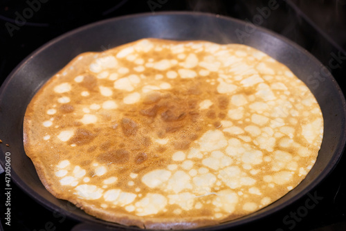 Frying pan with pancake isolated over white background