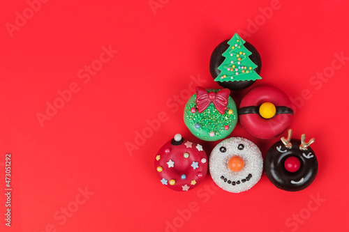 Christmas tree from colorful donuts on red background. Creative Minimal holiday concept. 