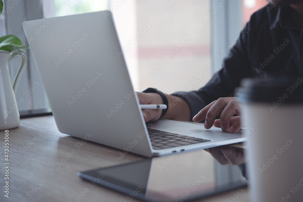 Close up of business man using, typing on laptop computer keyboard, online working from home office with digital tablet on wooden table Close up of business man using, typing on laptop computer keyboard, online working from home office with digital tablet on wooden table
