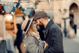 Christmas couple having romantic moments outdoors on Christmas. A young couple is standing on the street, holding hands and giving Eskimo kisses on New Year's Day.