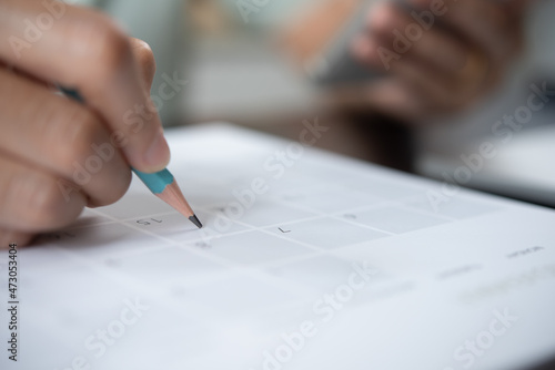 Event planner timetable agenda plan on schedule event. Business woman checking planner on mobile phone, taking note on calendar desk on office table