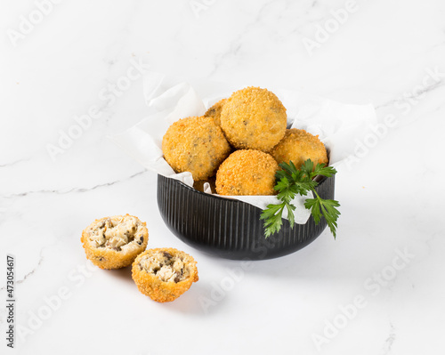 Mushroom Croquettes, balls with chicken, cheese and parsley in a serving bowl on a white background