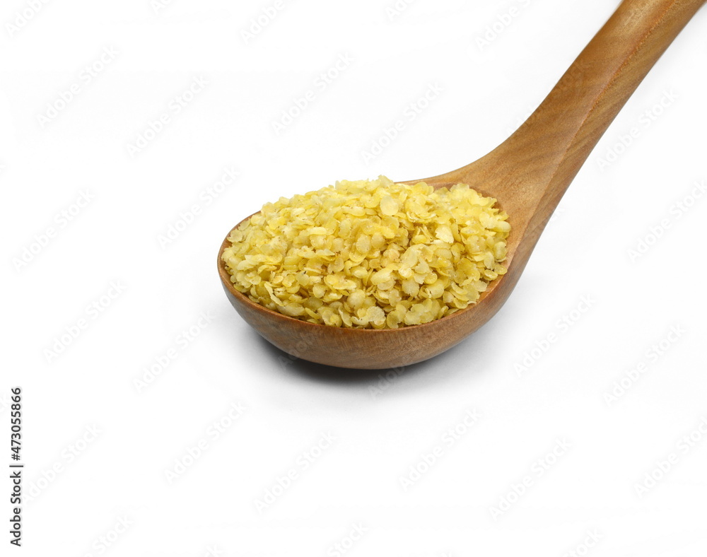 Millet flakes in a wooden spoon isolated on white bacground. Millet flakes in a wooden spoon isolated on white bacground.