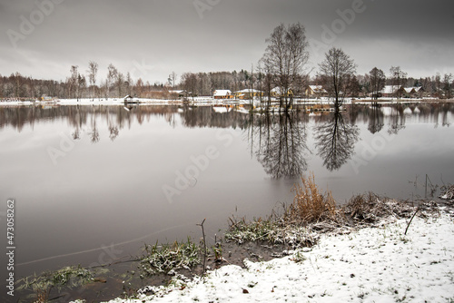 Landscape with lake, island, snow and buildings, Vecumnieki, Latvia photo