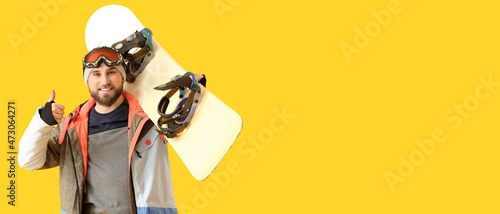 Fotografi Male snowboarder showing thumb-up gesture on color background with space for tex