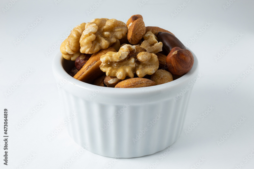 Small portion of roasted chestnuts and walnuts, in a white ceramic pot Small portion of roasted chestnuts and walnuts, in a white ceramic pot