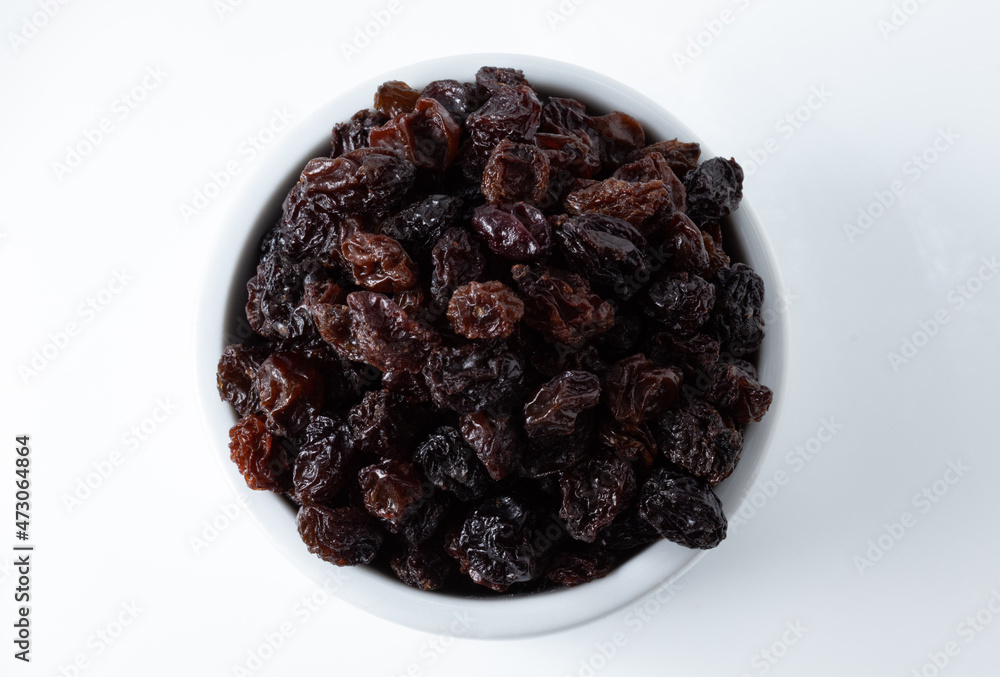 Top view of portion of dried dark raisins in white ceramic pot, on white background Top view of portion of dried dark raisins in white ceramic pot, on white background